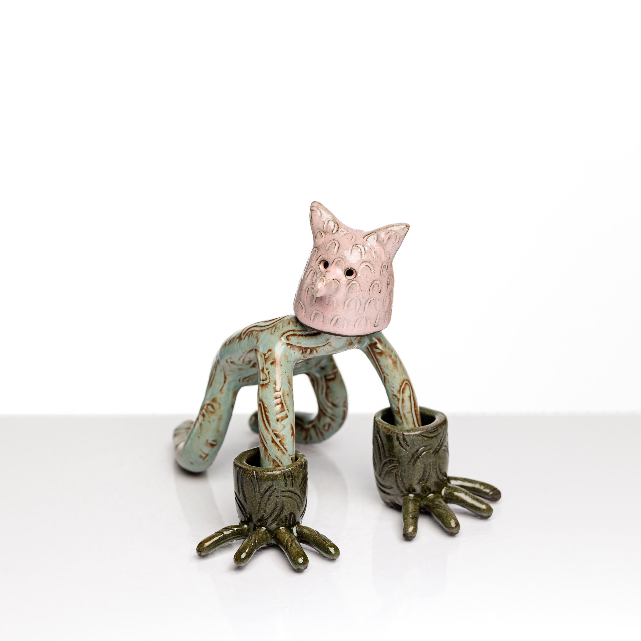 Sculpture en céramique par Fanny Mesnard. Un personnage avec une tête de chien et des gants de grenouille se tient à quatre pattes.