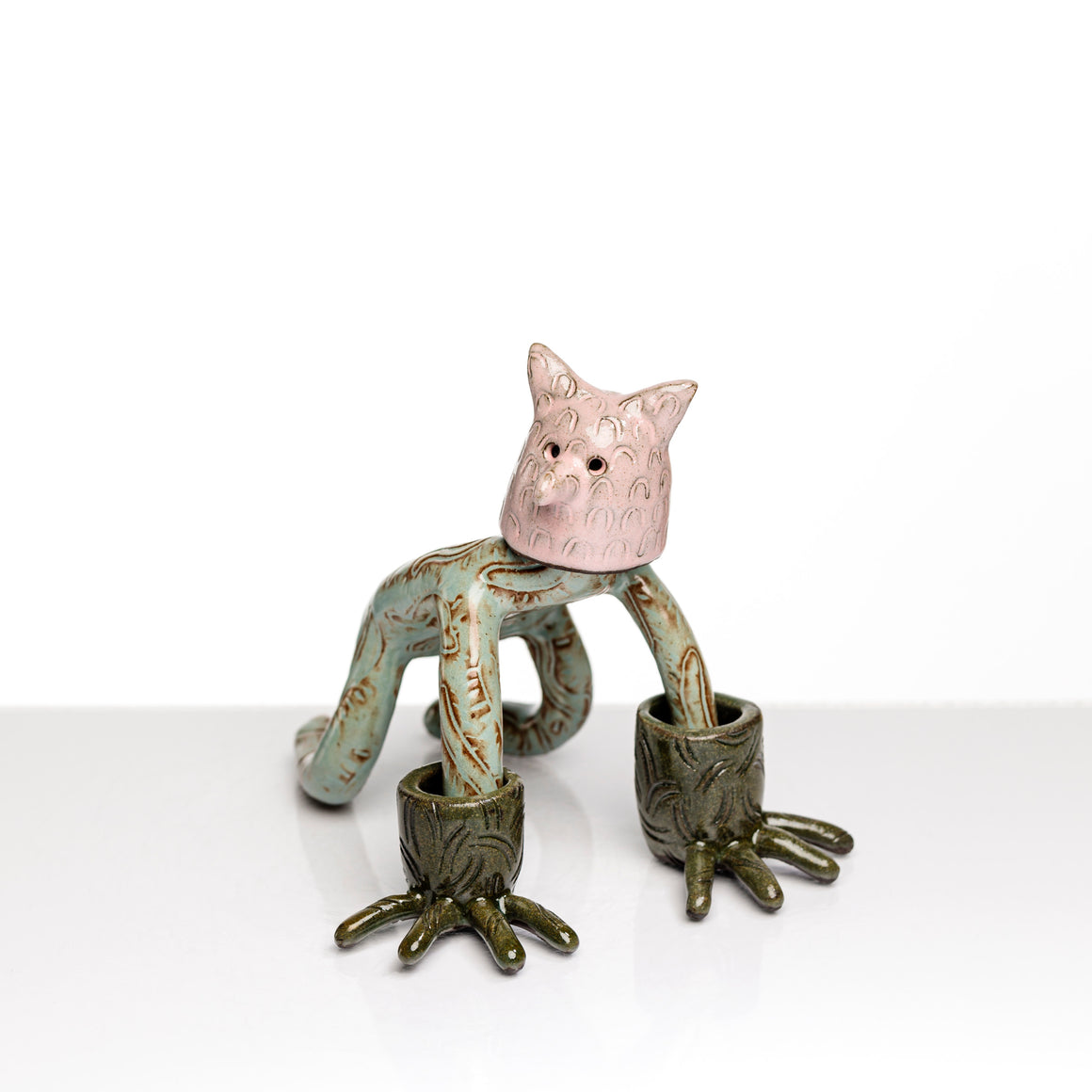 Sculpture en céramique par Fanny Mesnard. Un personnage avec une tête de chien et des gants de grenouille se tient à quatre pattes.