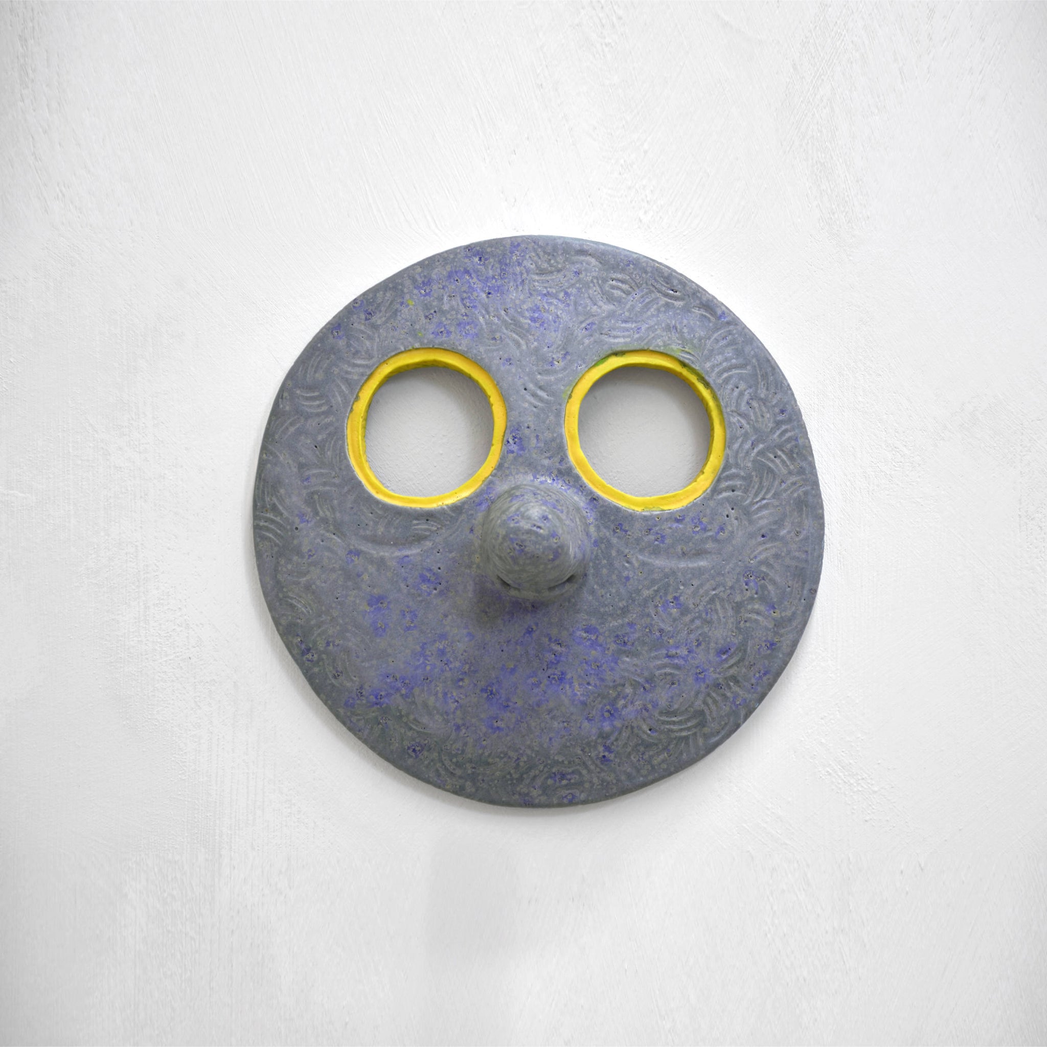 Masque mural en céramique de Fanny Mesnard. Un visage bleu au grand nez et aux yeux jaunes.
