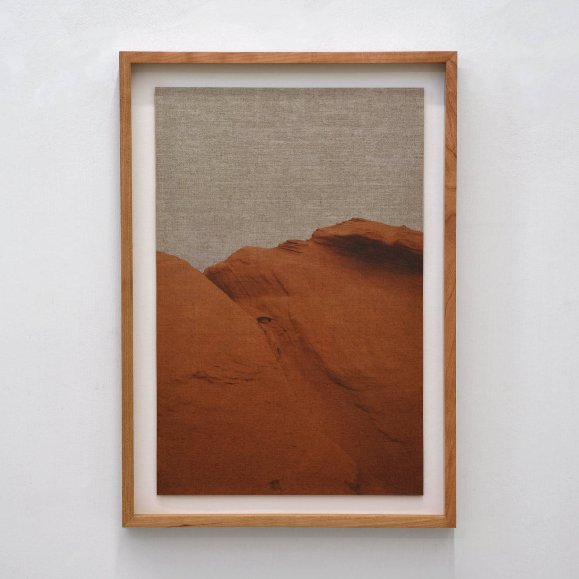 Grès, par Alphiya Joncas. Photographie (tirage unique) d’une colline orangée des Îles de la Madeleine. Impression sur lin naturel. Cadre en cerisier.