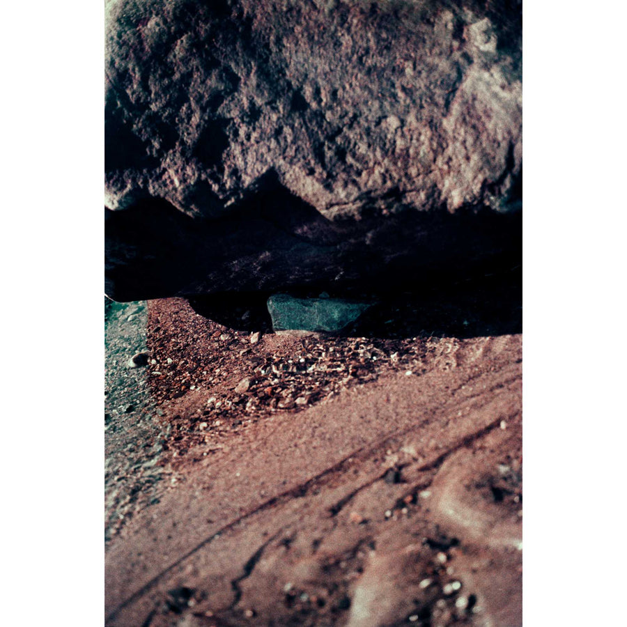 L’indépendante, par Éva-Maude TC. Photographie contemporaine sur pellicule 35 mm, 16” x 24”, 2024. Un caillou bleu se cache entre deux rochers roses de bord de fleuve.
