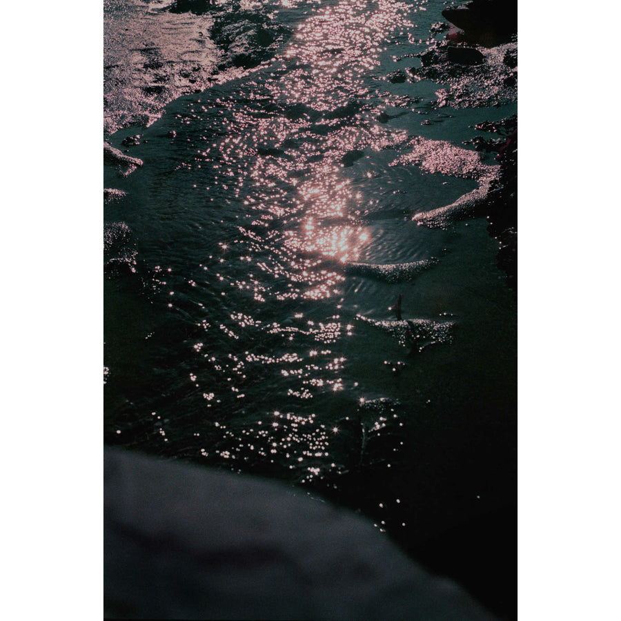 Les choses qui brillent II, par Éva-Maude TC. Photographie sur pellicule 35 mm, 12” x 18”, 2024. Éclat de lumière sur l’eau du fleuve à marée basse. Clair-obscur.