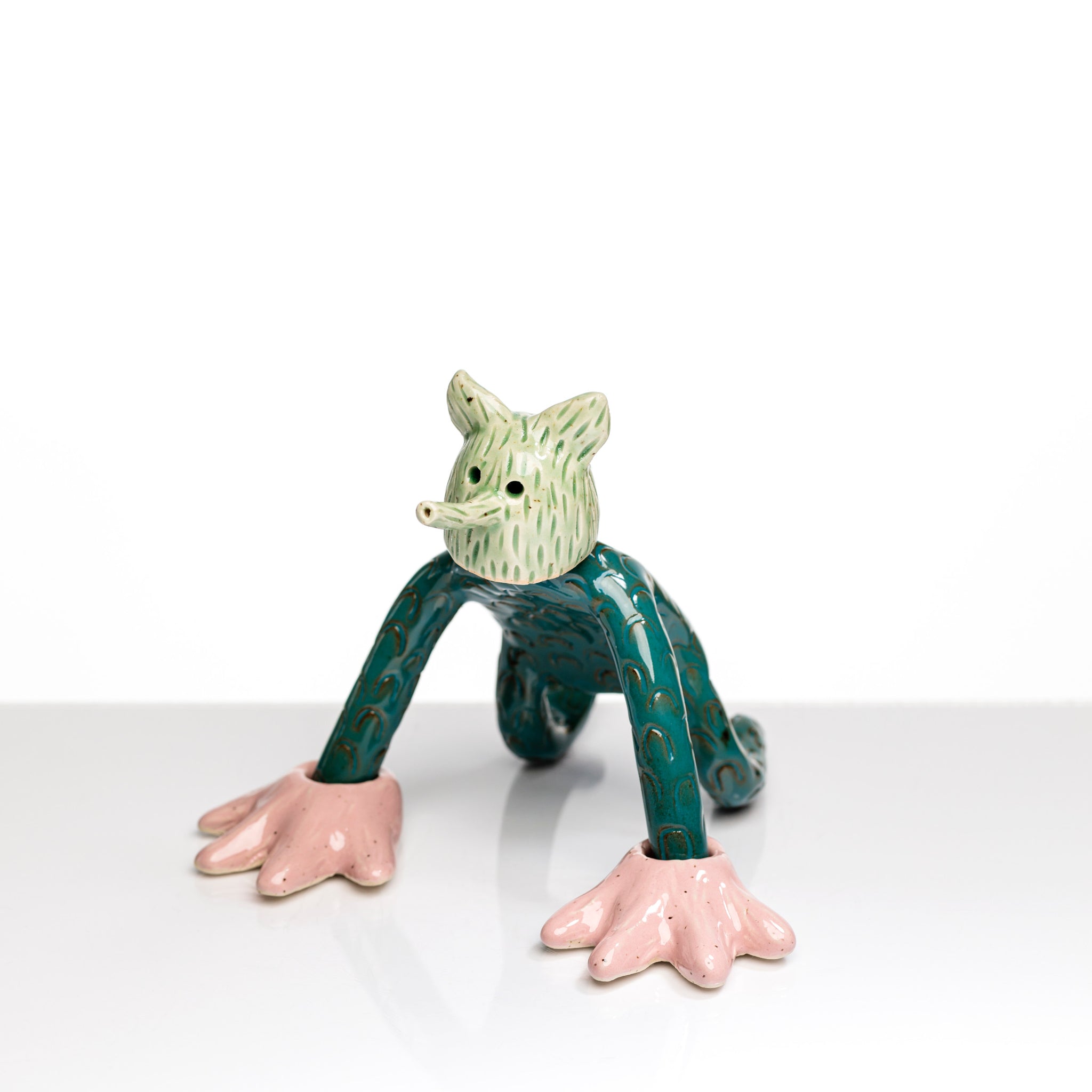 Sculpture en céramique par Fanny Mesnard. Un personnage avec une tête au nez trompette et des pattes roses est à quatre pattes.