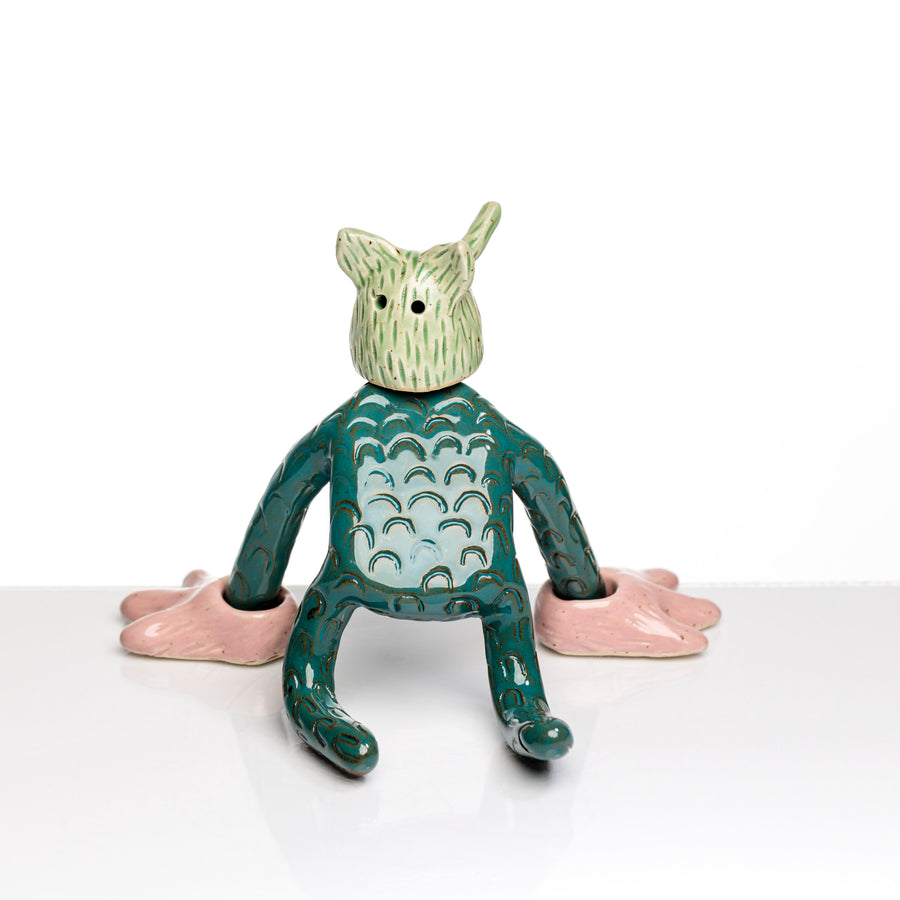 Sculpture en céramique par Fanny Mesnard. Un personnage avec une tête au nez trompette et des pattes roses est à quatre pattes.