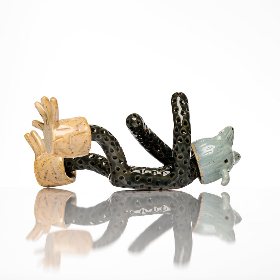 Sculpture en céramique par Fanny Mesnard. Un personnage avec une tête d’ours et d’oiseau est en perte d’équilibre sur le dos.