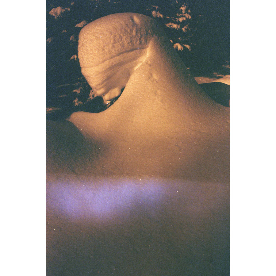 Portrait du fantôme d’hiver, par Éva-Maude TC. Photographie contemporaine sur pellicule 35 mm, format vertical de 24” x 36”. Forme humaine dans la neige, décor nocturne, lumière violette sur fond orangé.