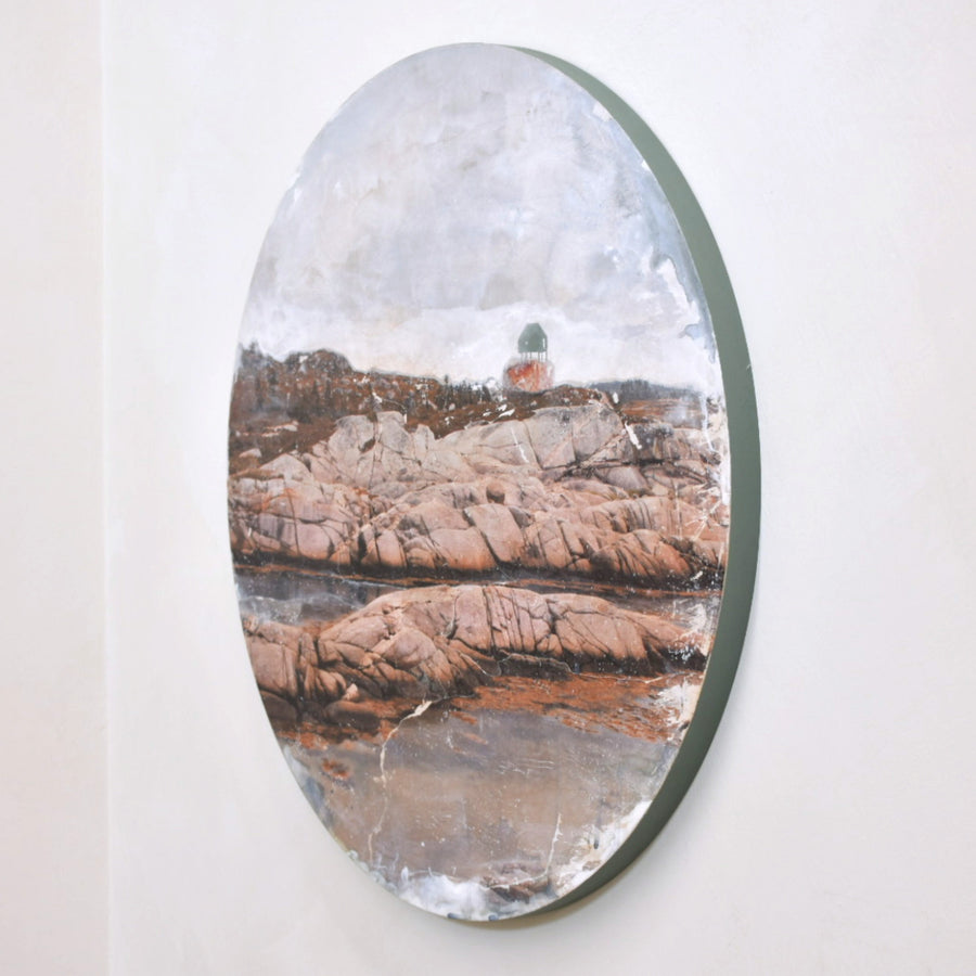 Tableau circulaire de l’artiste multidisciplinaire Caroline Bolieu. Une maison est posée, debout, sur des rochers en bord de mer.