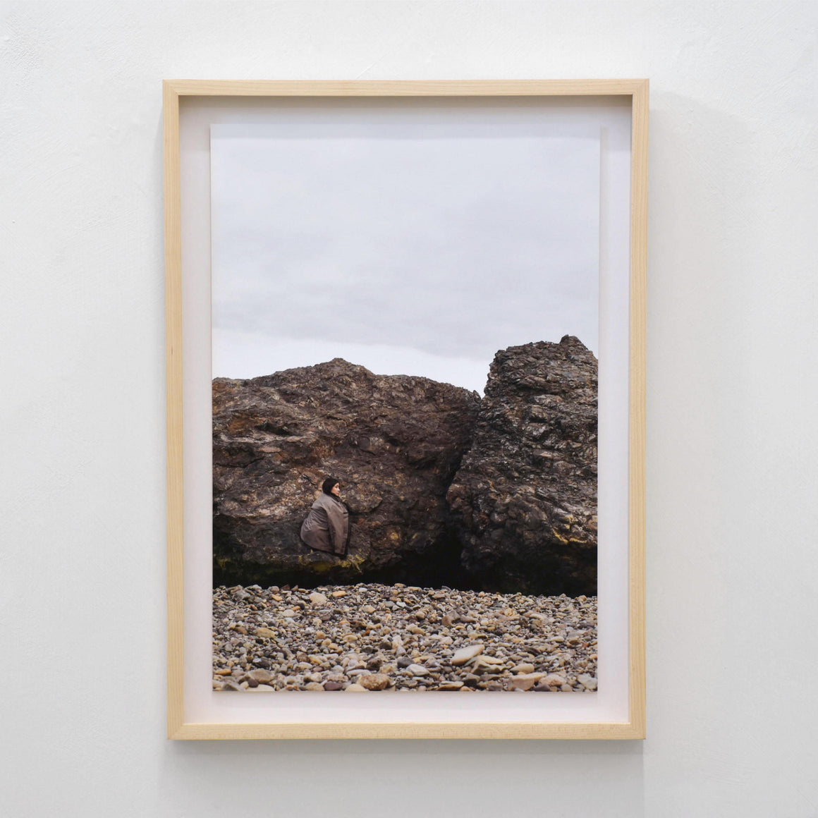 Rocher II, par Alphiya Joncas. Autoportrait de la photographe, recroquevillée sur un gros rocher brun des Îles de la Madeleine. Tirage limité.