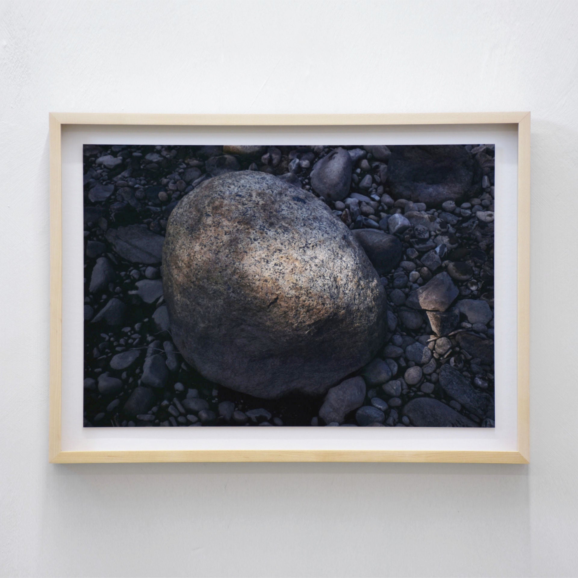 Rocher, par Alphiya Joncas. Photographie d’un rocher éclairé par un rayon de soleil sur une plage des Îles de la Madeleine. Tirage limité, cadre en érable.