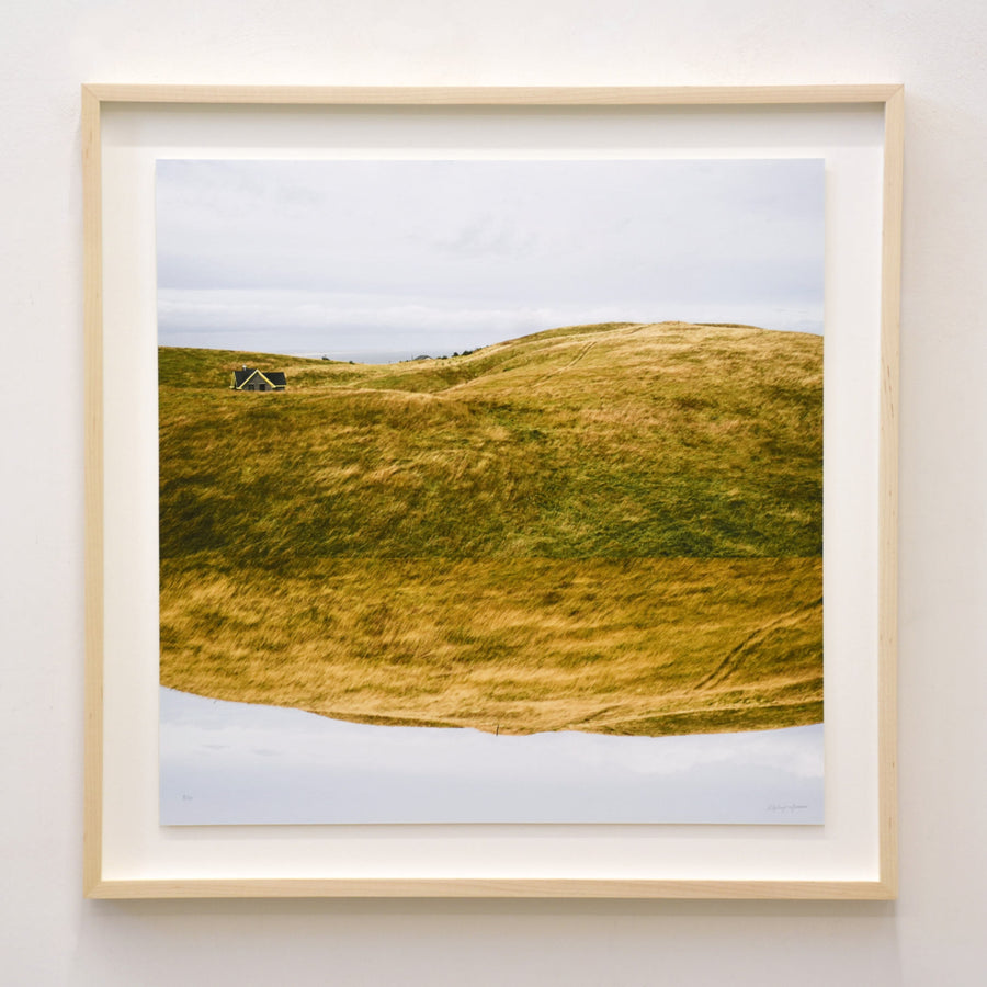 S’abriter dans les buttes, par Alphiya Joncas. Photographie des collines jaunes des Îles de la Madeleine, avec une maison qui s’y cache.