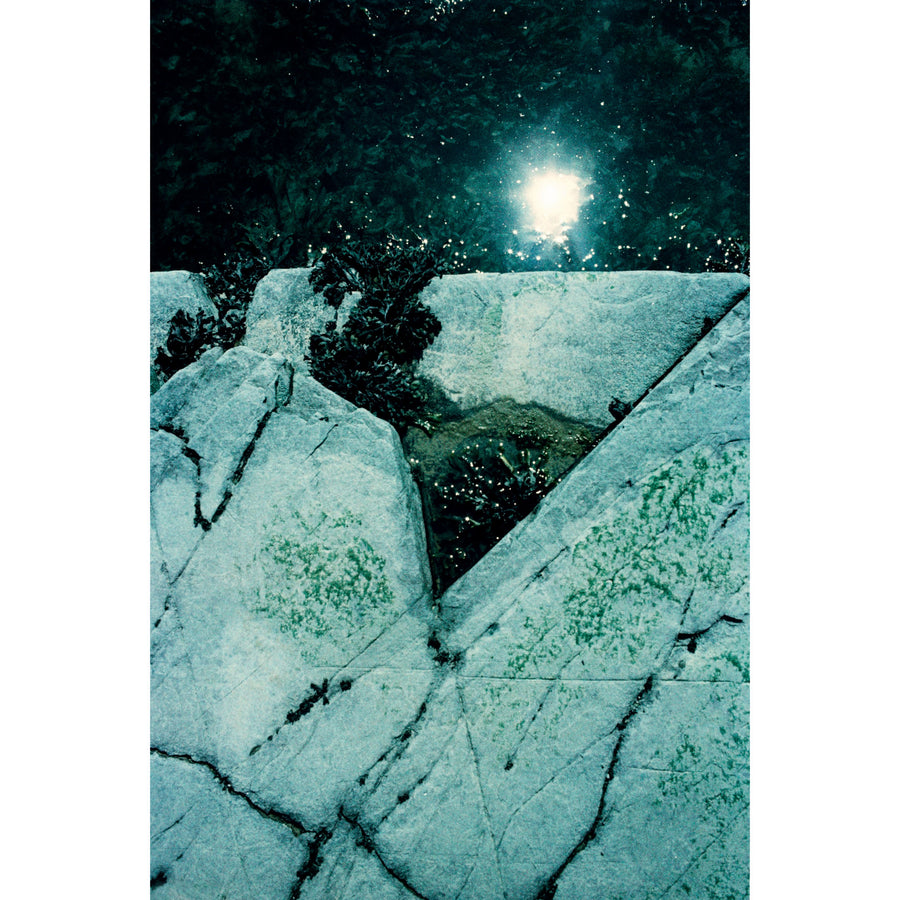 Triangle désamorcé, par Éva-Maude TC. Photographie sur pellicule 35 mm, tirage limité de 4 exemplaires. Nuances de vert et de turquoise, reflet du soleil dans l’eau, rocher de rivage.