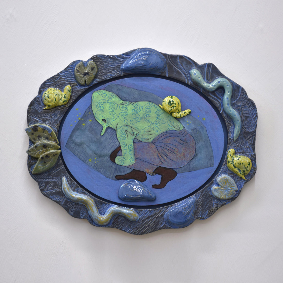 Oeuvre unique de Fanny Mesnard. Acrylique sur toile et encadrement en céramique. Un personnage déguisé est entouré par une faune de sous-bois.