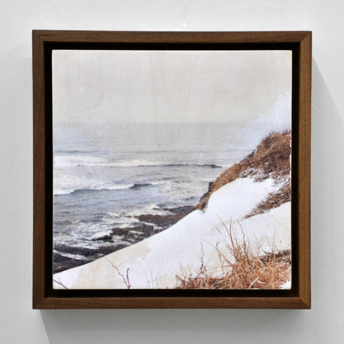 La romance du Saint-Laurent, par Caroline Bolieu. Acrylique et transfert photographique sur bois. Rivage avec neige et herbes rousses sur le bord du fleuve, au printemps.