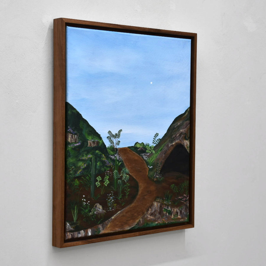 Sans titre, de Gabriel Rioux. Acrylique sur toile, 16” x 20”, cadre en noyer, 2022. Peinture de paysage, genre naïf, ciel bleu pâle et grotte sur colline verte.